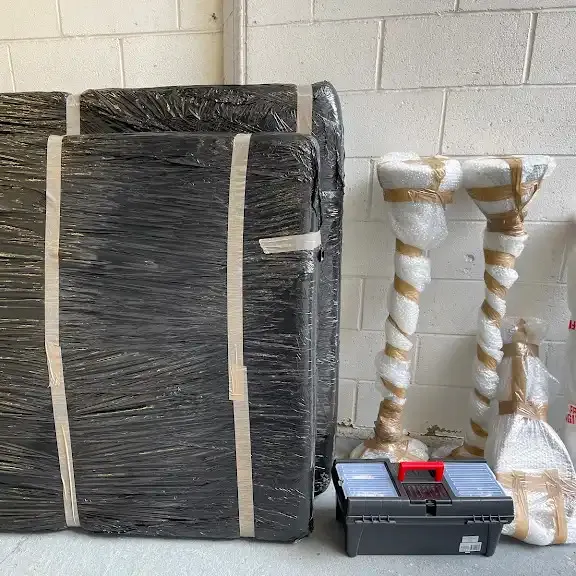 A large item shrink-wrapped and strapped, with padded legs alongside