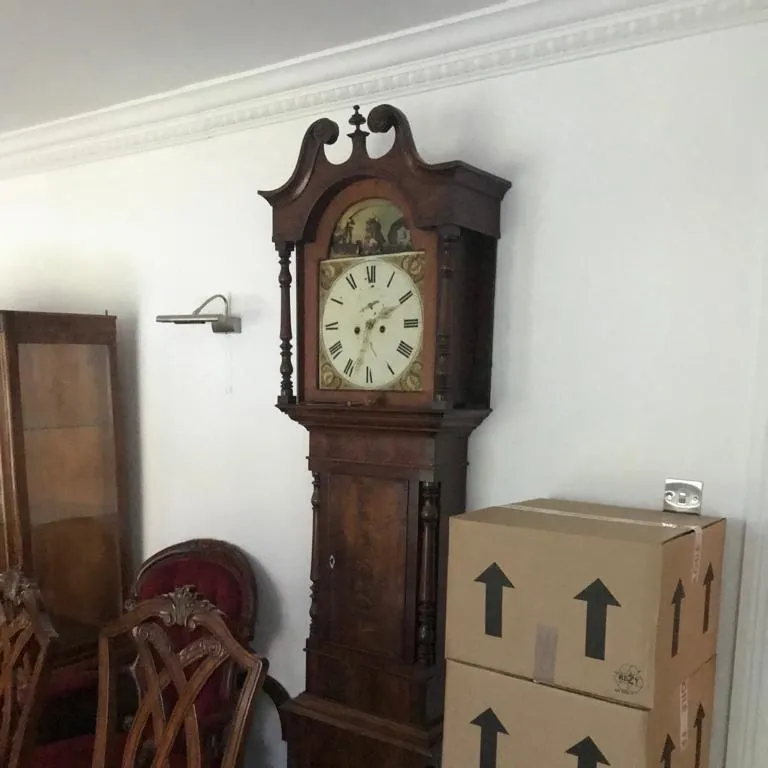 A longcase clock standing beside stacked removal cartons